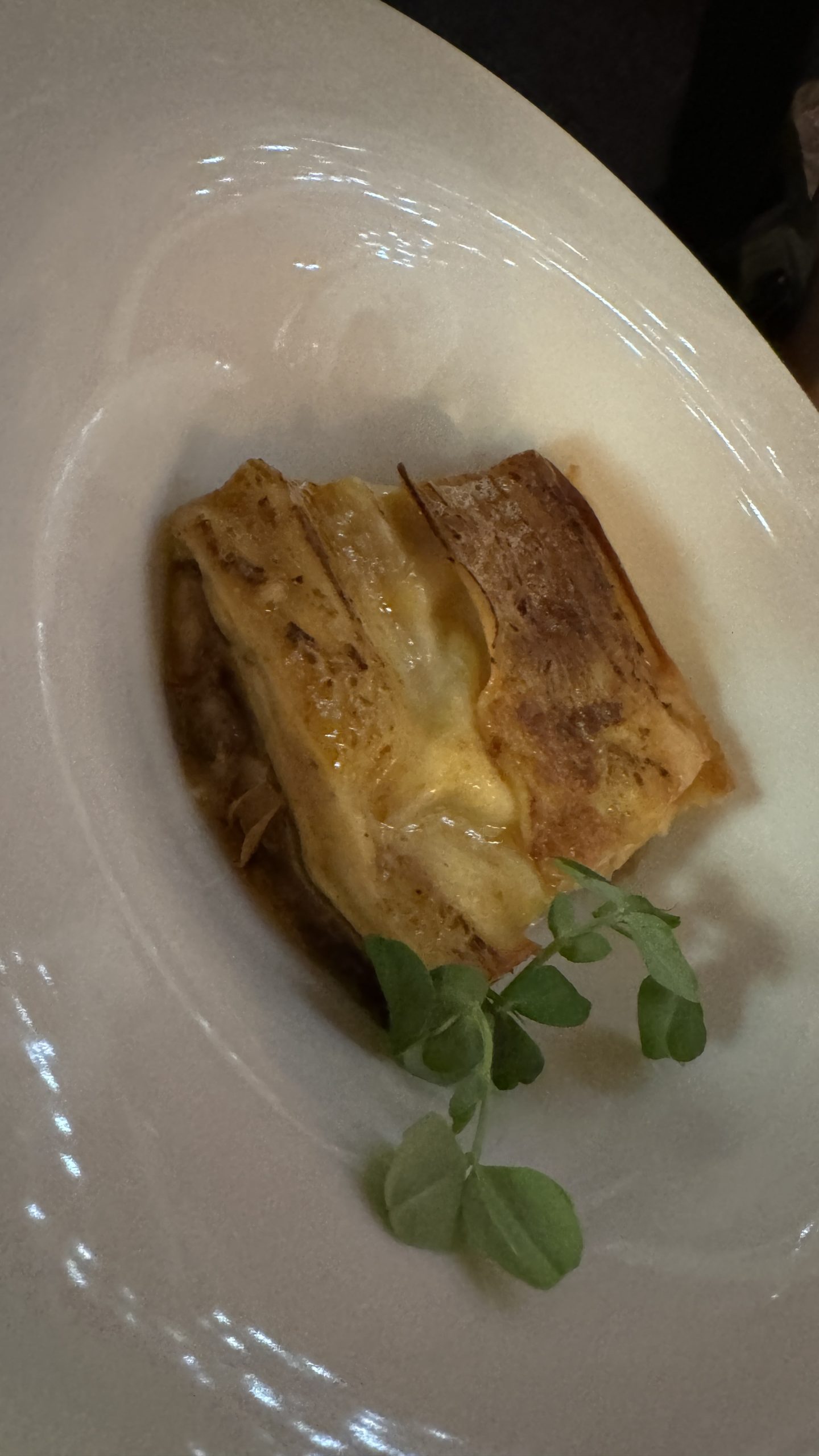 Golden baked savory course served in a wide white bowl with herbs at a restaurant in the Langhe.