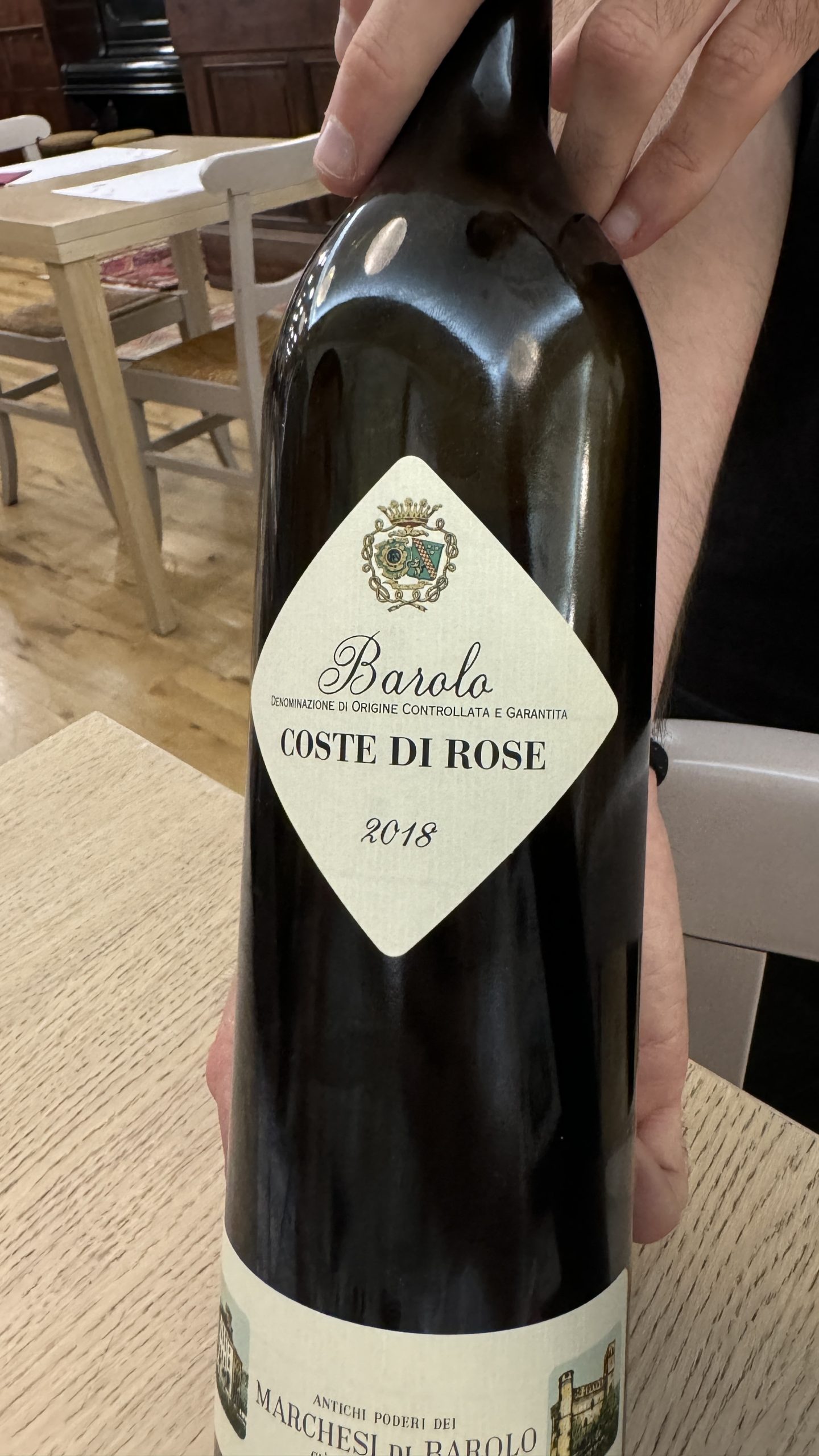 Bottle of Barolo wine held at a table during a visit to the Langhe.