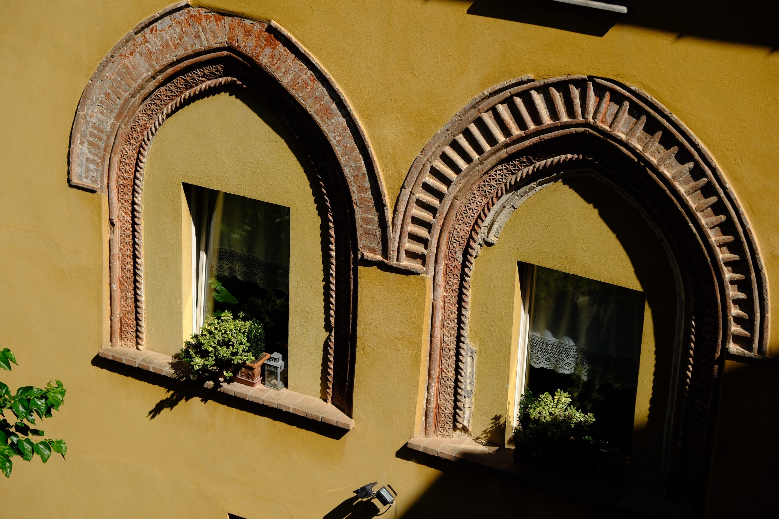 Decorative brick arches framing windows on a golden building in the Langhe.