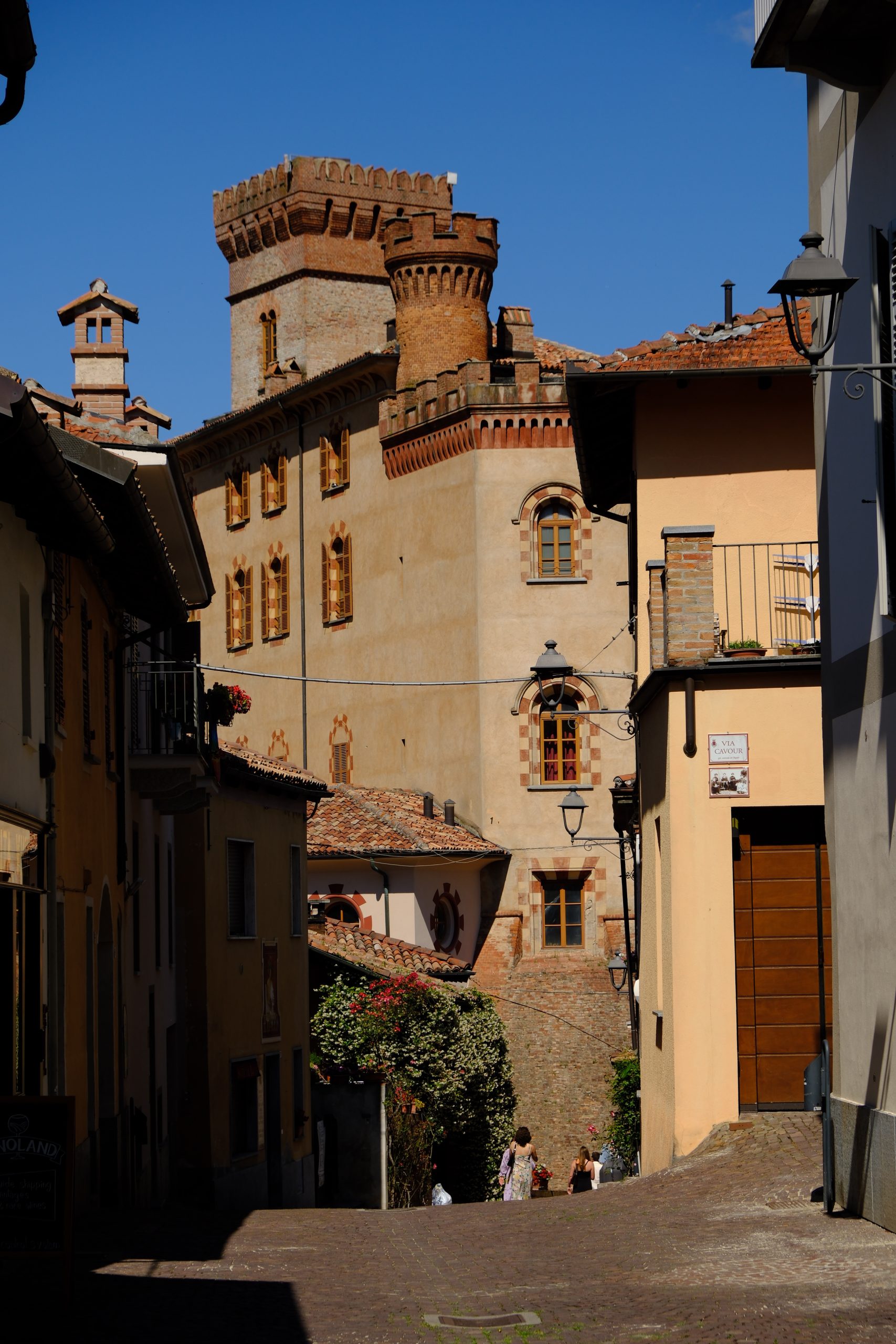 Warm-toned historic street climbing through a village in the Langhe hills.