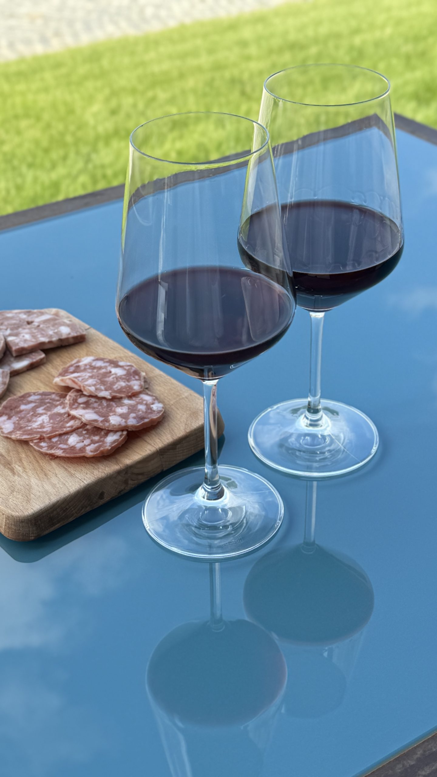 Two glasses of red wine beside a small board of charcuterie outdoors in the Langhe.