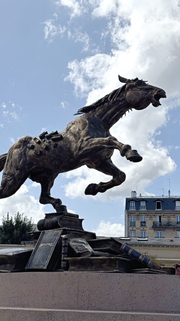 Dramatic bronze horse statue in Maisons-Laffitte beneath a blue sky.