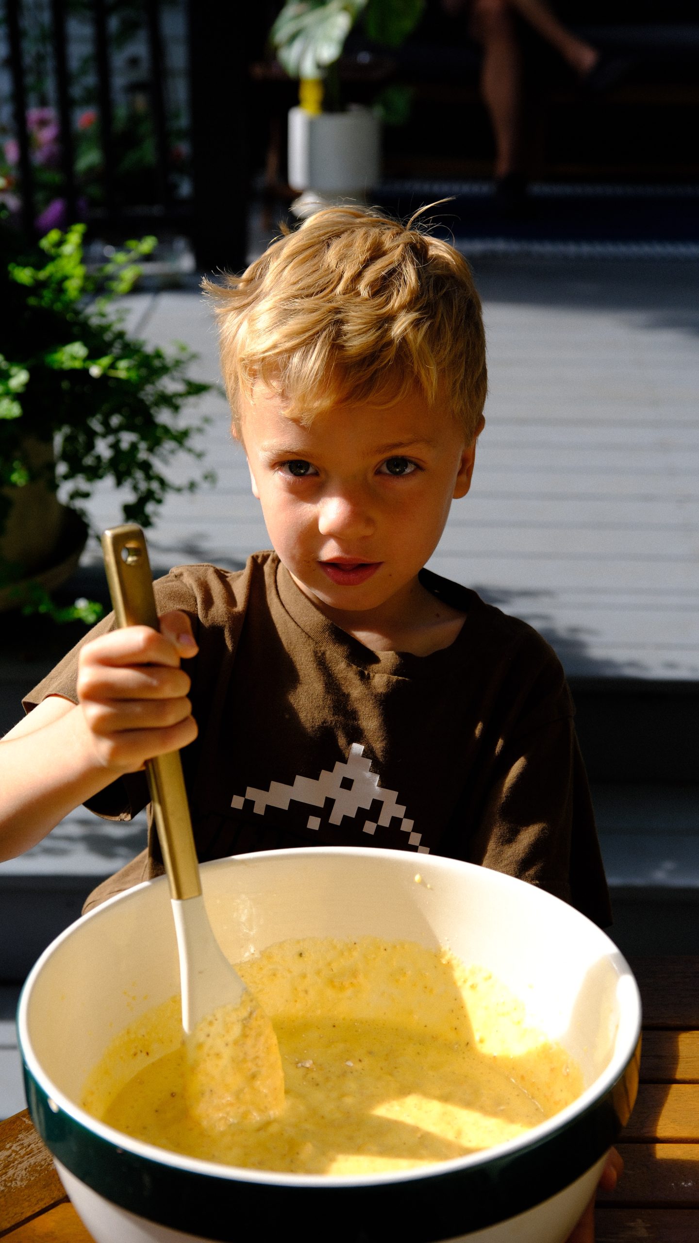 Six year old Christopher mixing hazelnut cake batter in a large bowl.