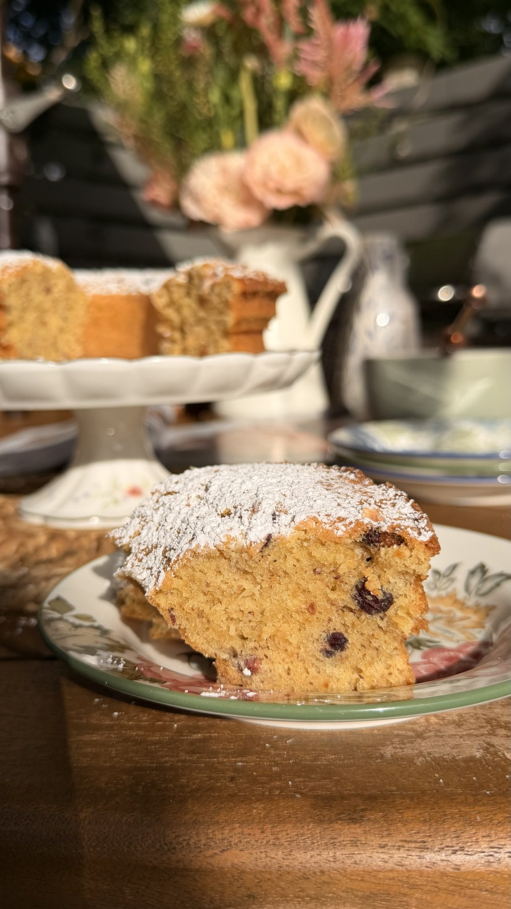 A thick slice of hazelnut cake dusted with powdered sugar on a floral plate.