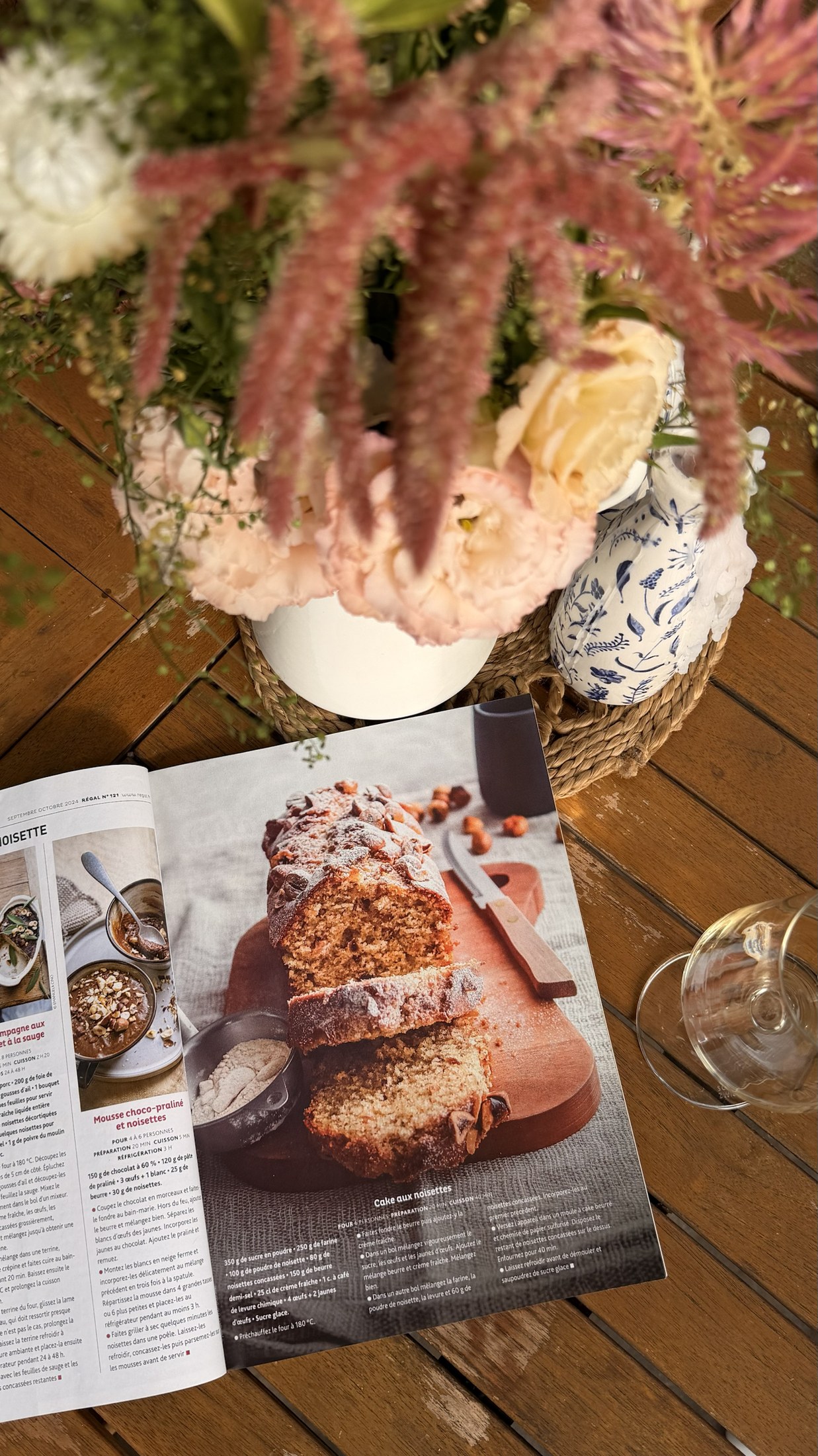 Régal magazine open to a hazelnut loaf cake recipe on a wooden table beside flowers.