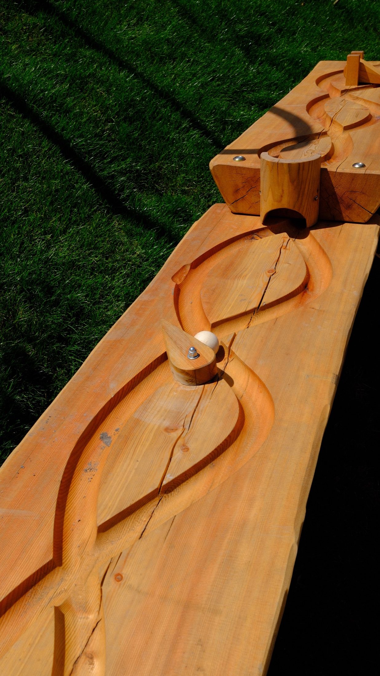 A carved wooden activity station beside the alpine playground