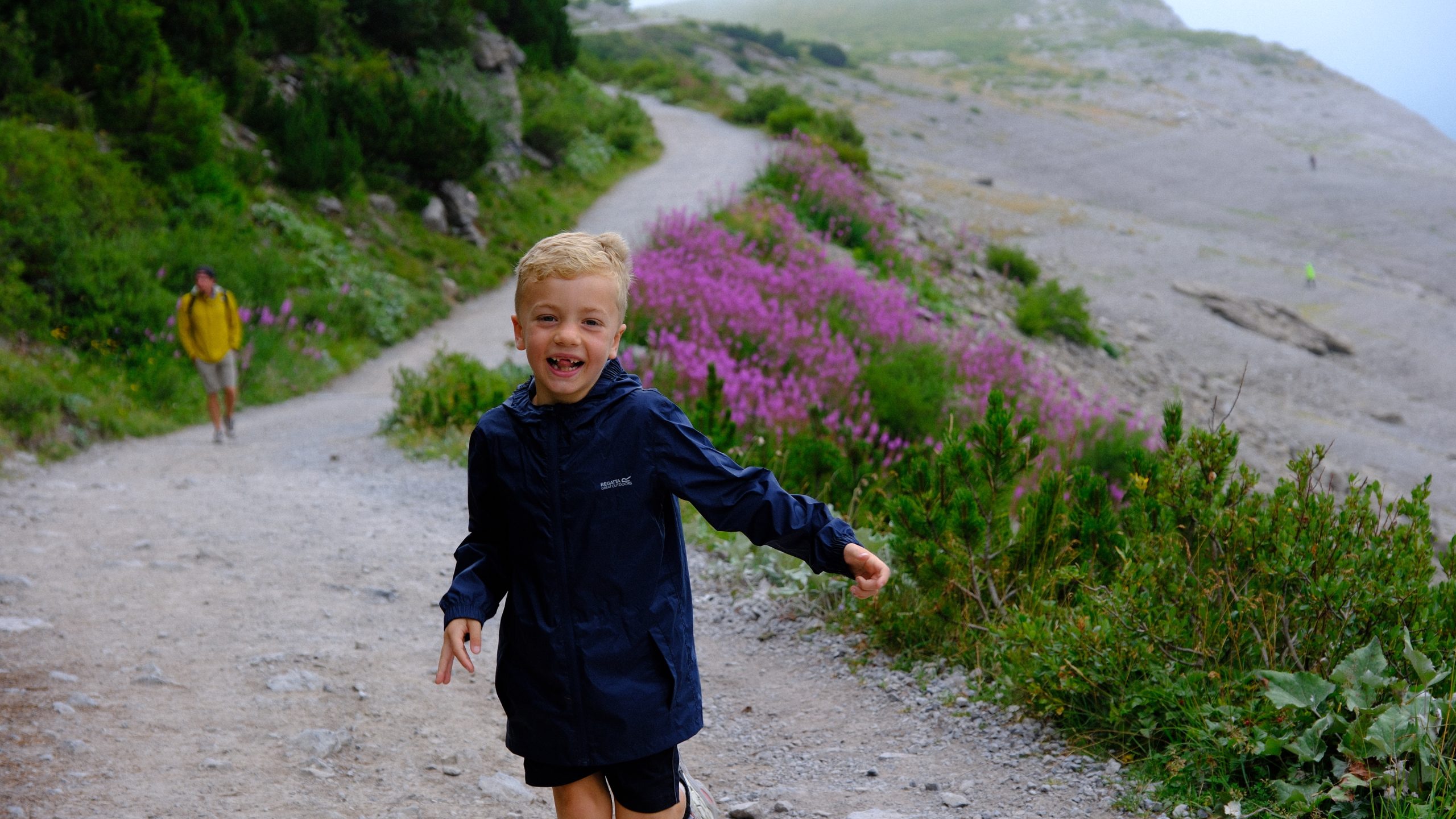Chris running happily along the Lünersee path with flowers and lake behind him.