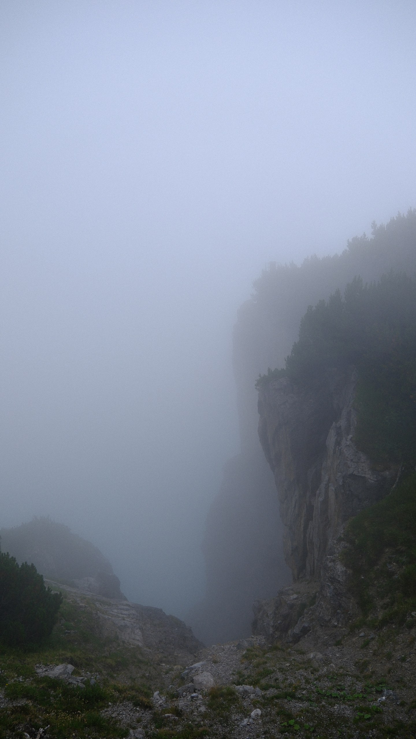 A narrow cleft between dark mountain rocks filled with pale fog.
