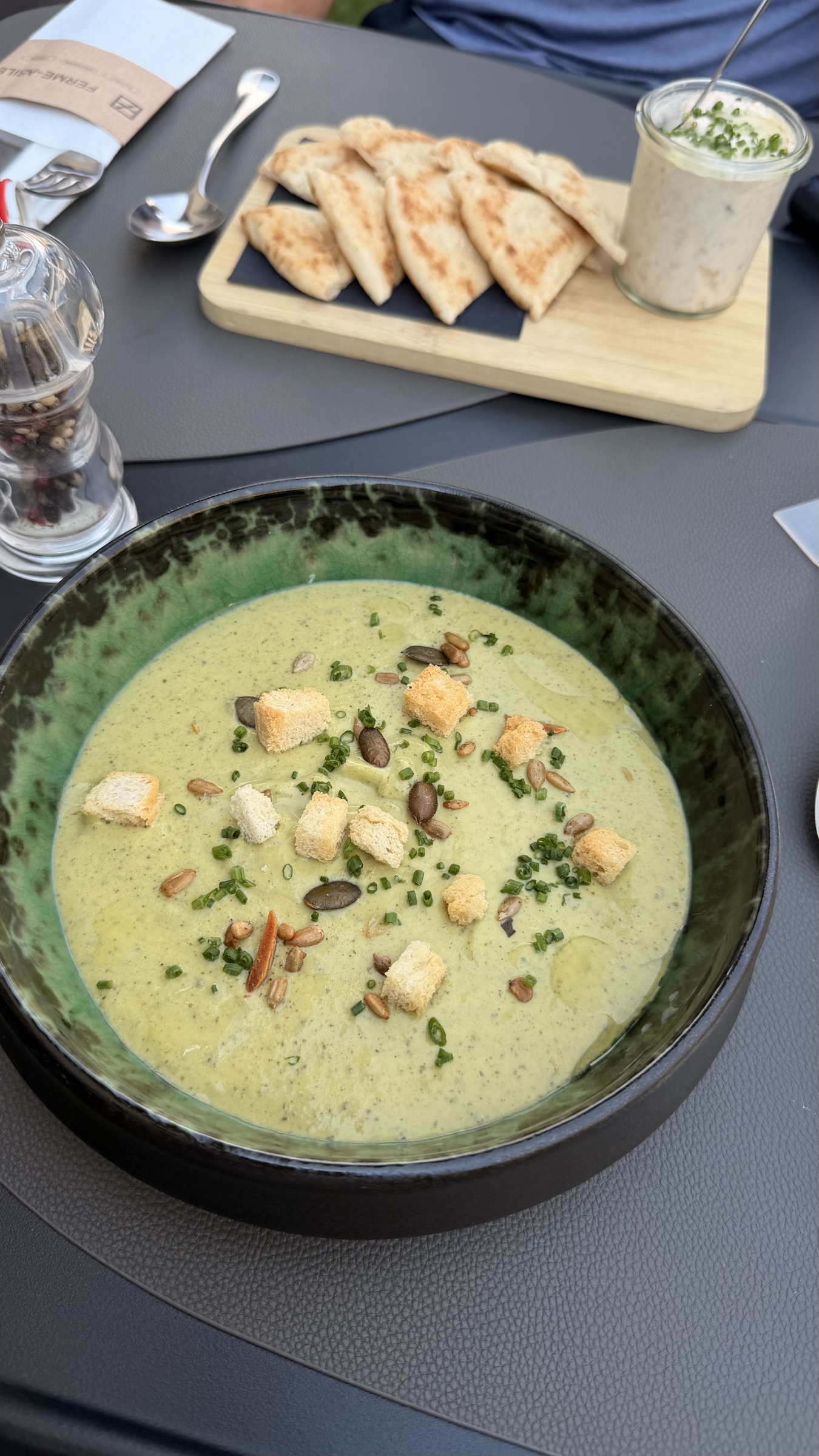 Pale green zucchini velouté at Ferme-Asile, finished with croutons, mixed seeds, chives, and olive oil.