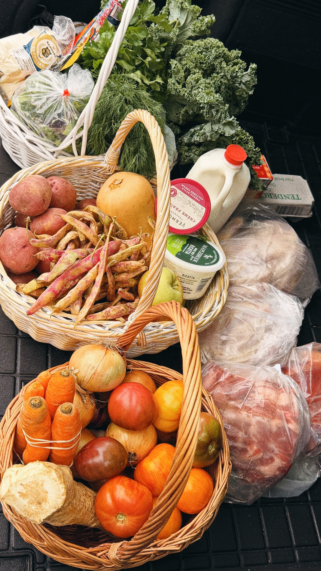 Baskets filled with squash, tomatoes, onions, carrots, beans, potatoes and greens after a visit to Tendercrop Farm.