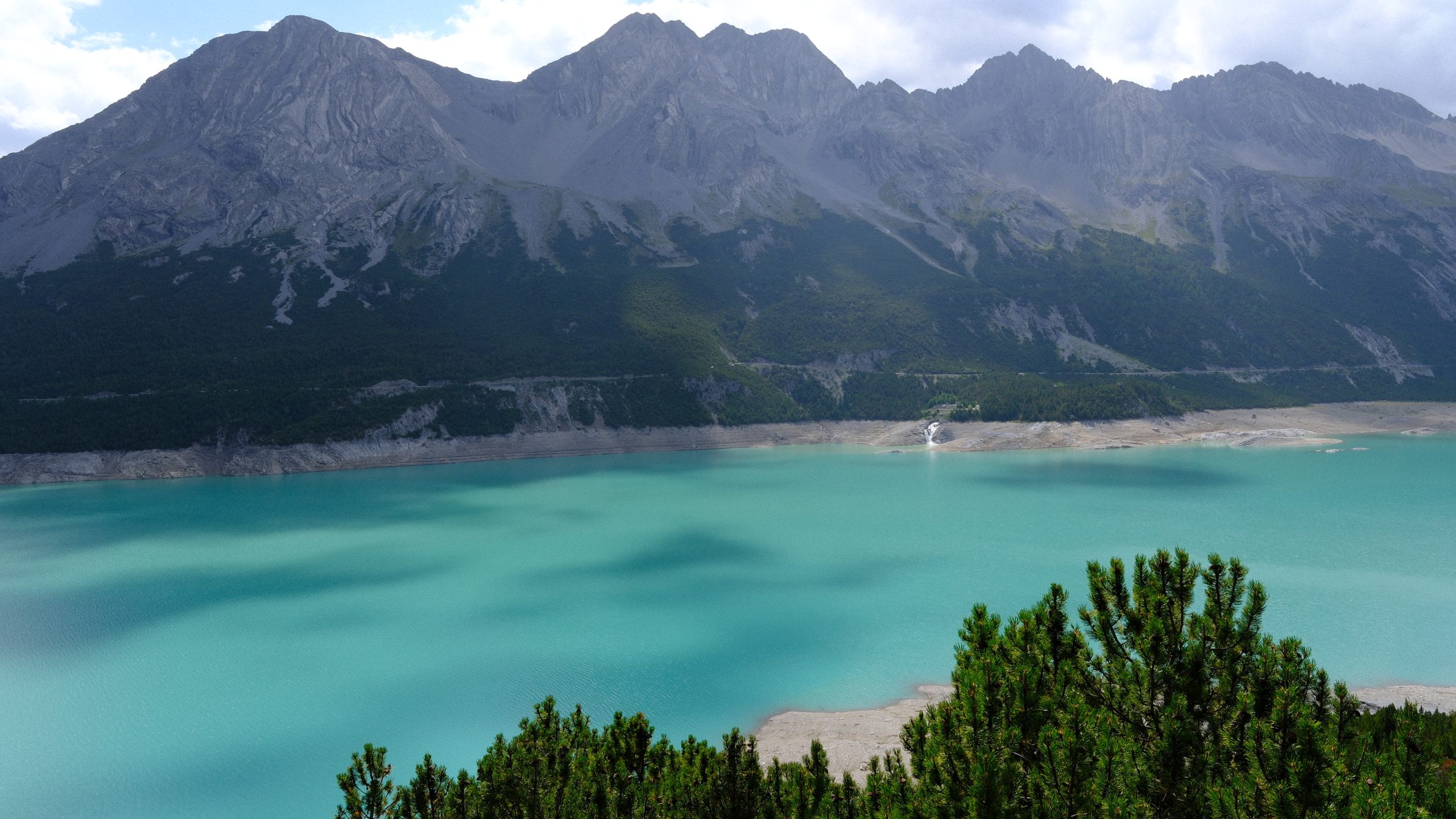 Milky turquoise water of Lago di Cancano beneath dark mountains
