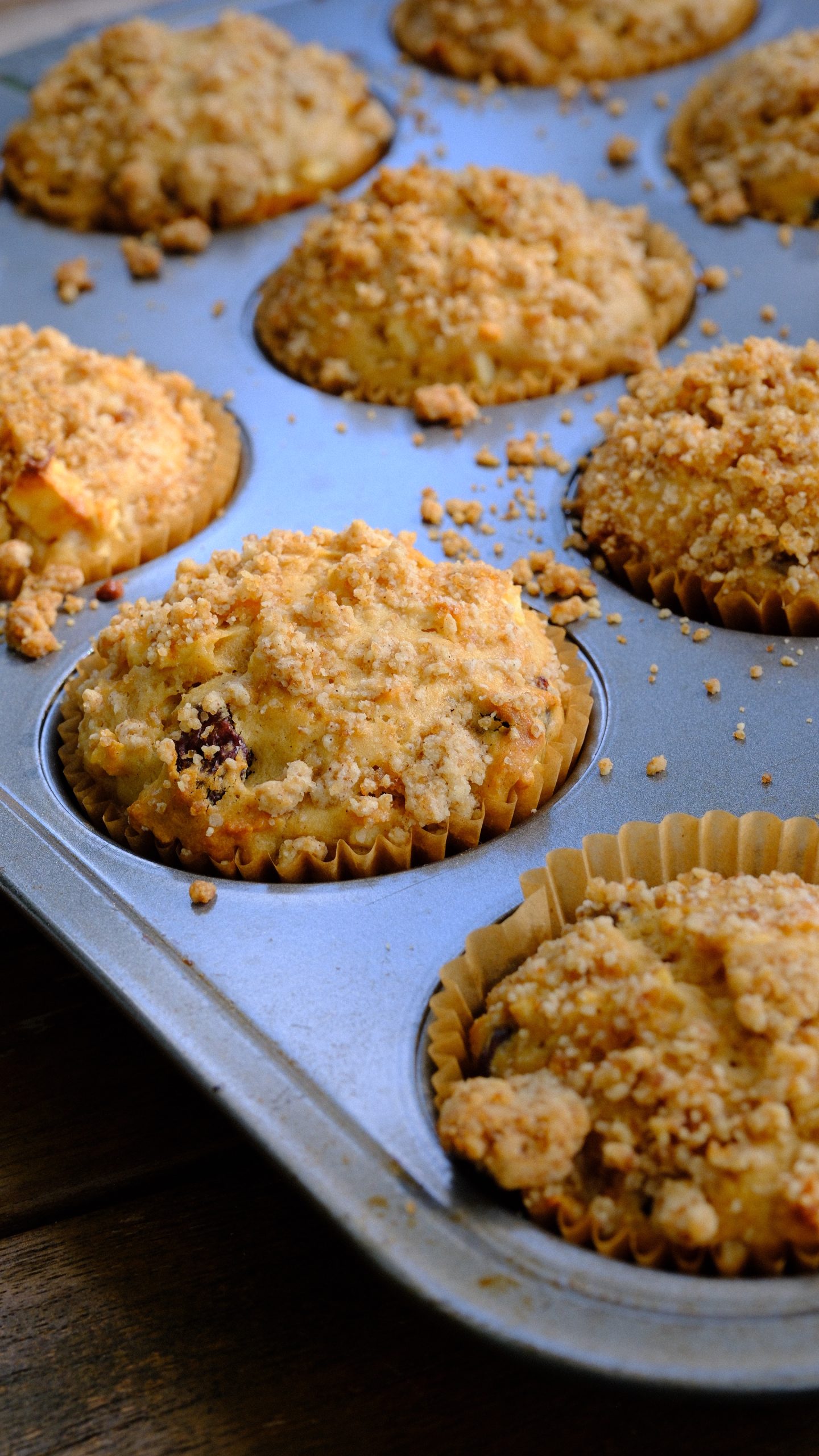 Apple cinnamon raisin muffins topped with brown sugar streusel in a muffin pan
