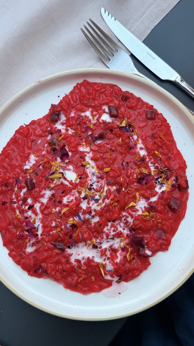 Bright beetroot risotto finished with cream and flower petals