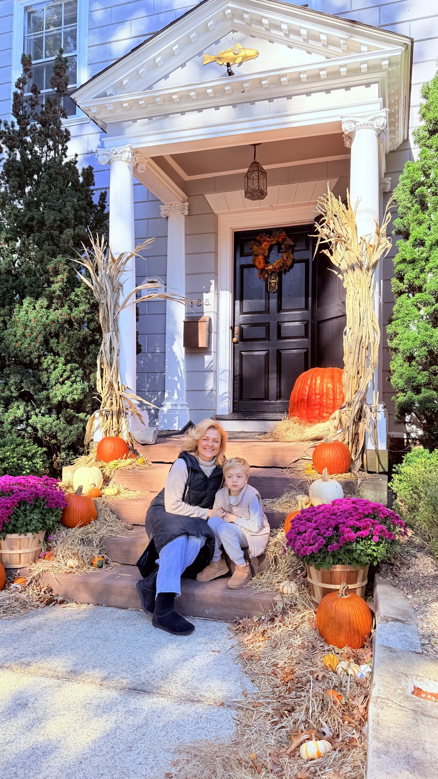 Karolina and Chris sitting together among pumpkins, hay, and autumn flowers