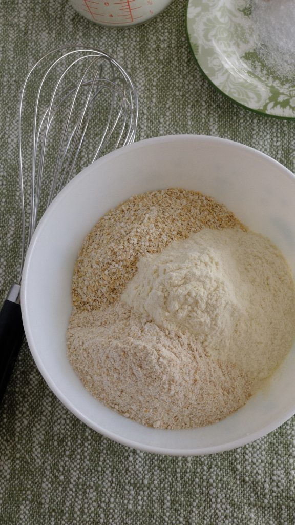 Bread flour, whole-wheat flour, and oat bran measured together in a white bowl