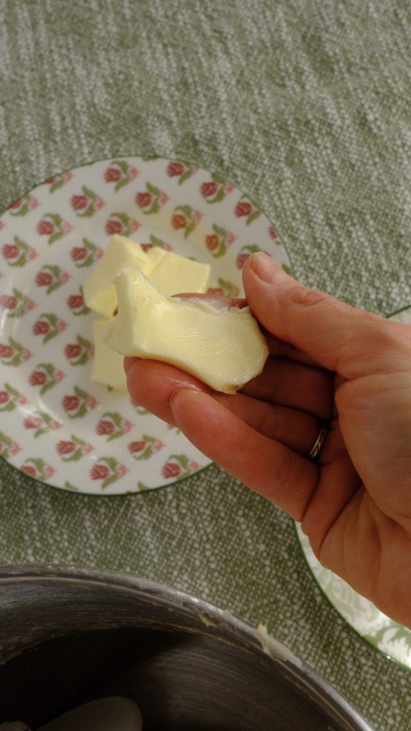 A piece of very soft butter held above the mixing bowl