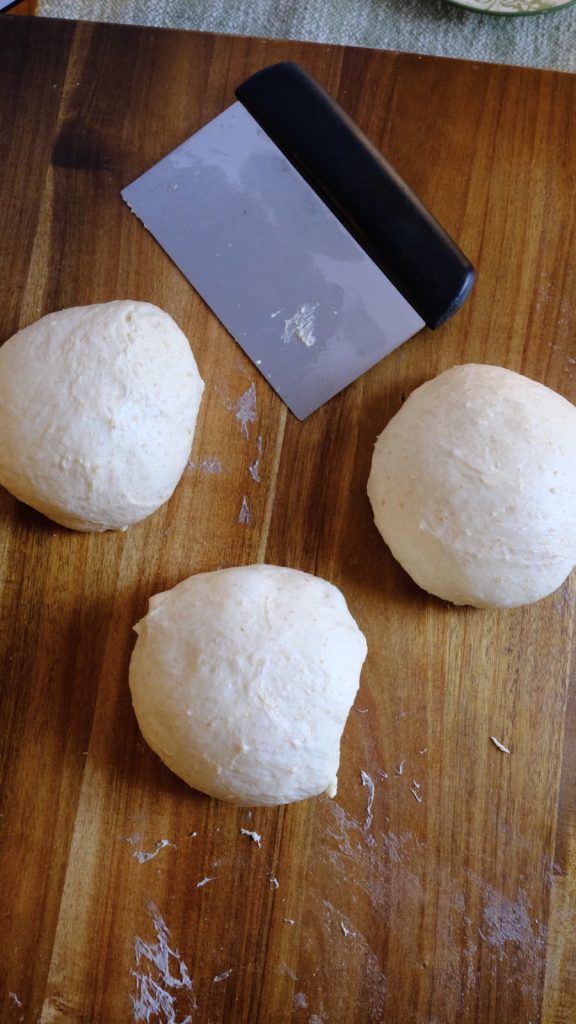 Bread dough divided into three equal portions on a wooden work surface