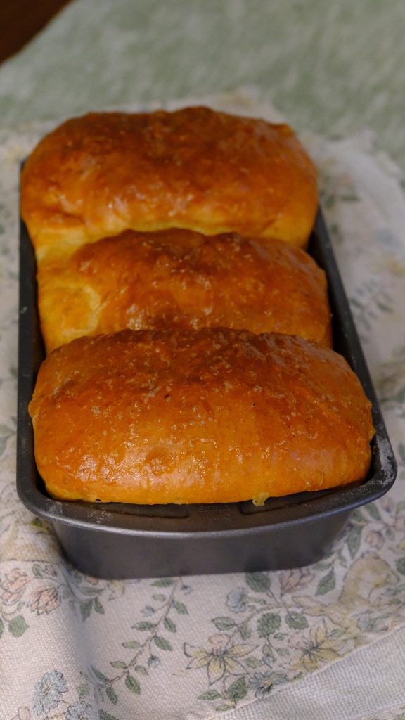 Golden whole wheat and oat bran milk bread baked in three joined sections in a loaf pan